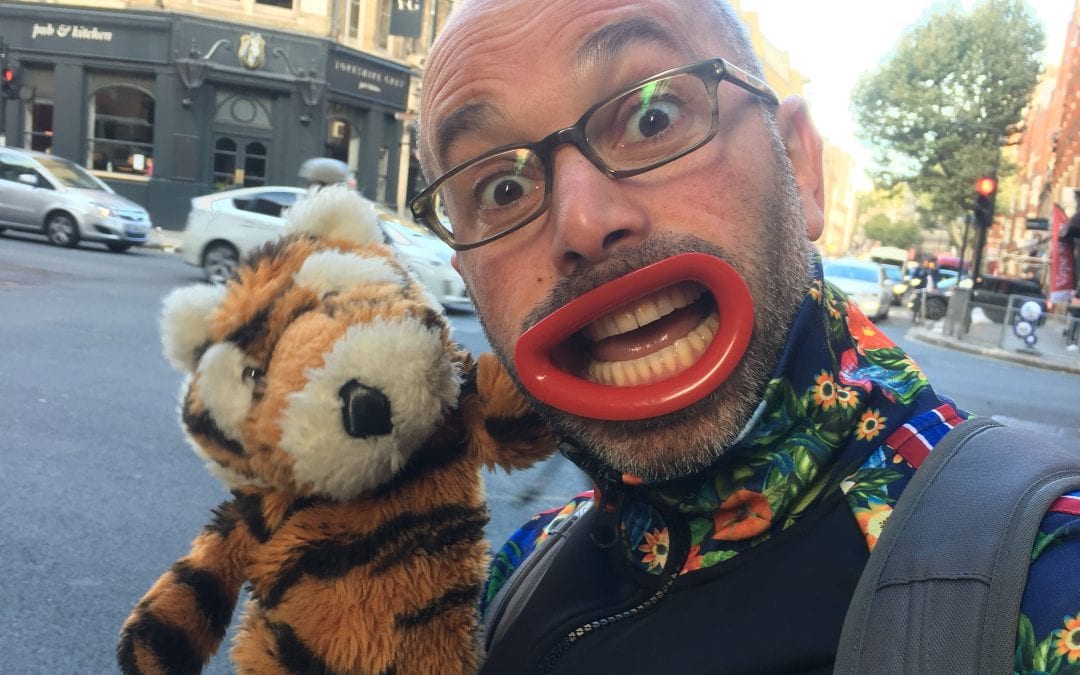 a man with large clown lips holding lion glove puppet