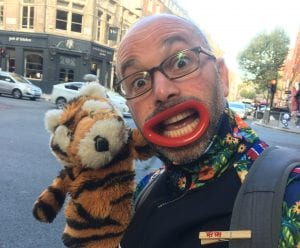 a man with large clown lips holding lion glove puppet