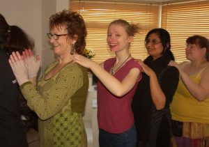 4 women in a line with hands on each others shoulders