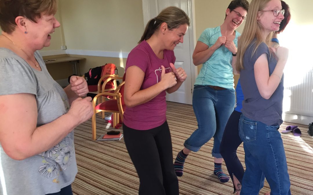 4 women wearing tshirts and jeans practicing Laughter Yoga