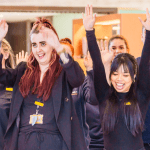2 women in black business dress laughing with arms in the air