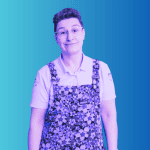 Woman in black and white image with short brown hair wearing dungarees looking glum on a blue background